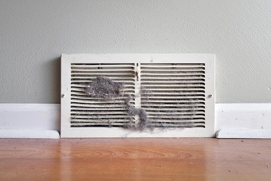 Dusty and clogged air vent near the floor.